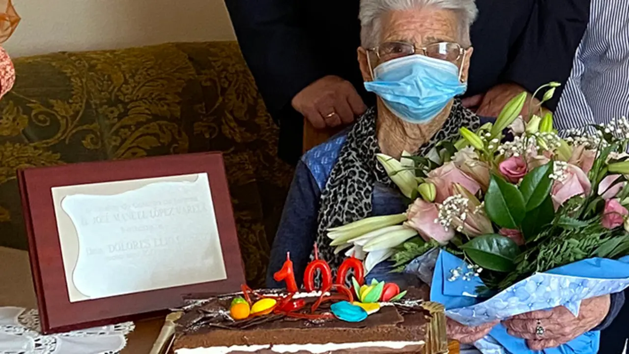 Dolores con las flores y junto a la placa conmemorativa de su aniversario